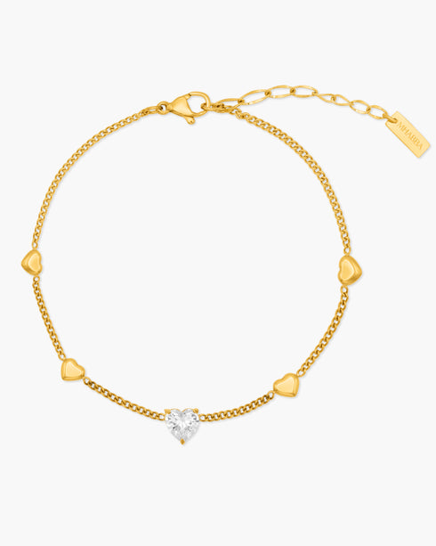 Gold bracelet with heart-shaped diamond on a white background